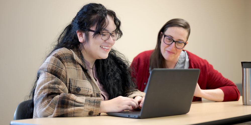 A student and teacher discuss a project during class